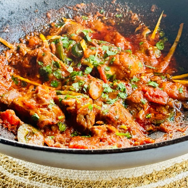 Close-up of Khan's Kitchen's Indian chicken curry with cilantro and ginger in a pan.