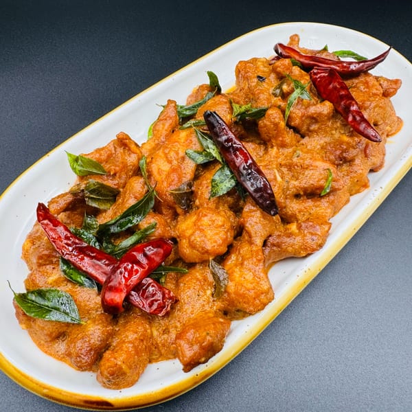 Khan's Kitchen Chicken 65, a spicy Indian fried chicken dish, garnished with curry leaves and red chilies.