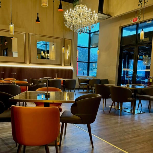 Khan's Kitchen dining room with modern tables, orange and brown chairs, and a large chandelier.