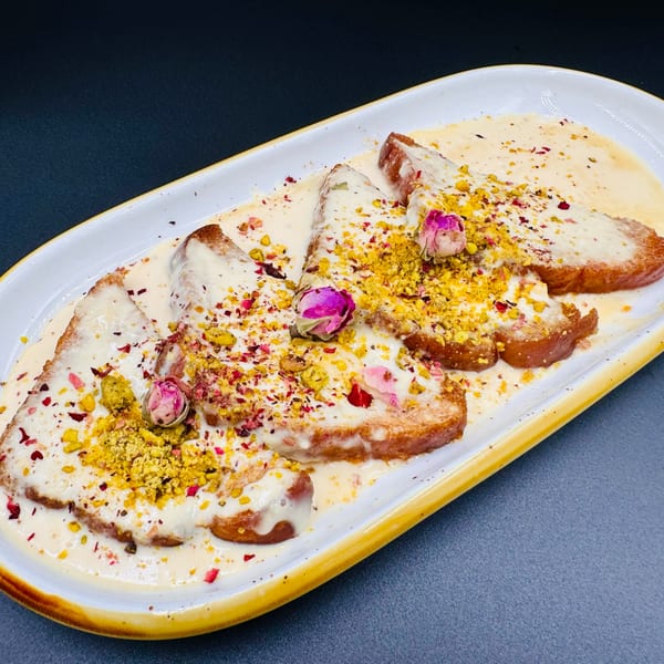 Shahi Tukda, an Indian bread pudding, topped with cream, pistachios, and rose petals.