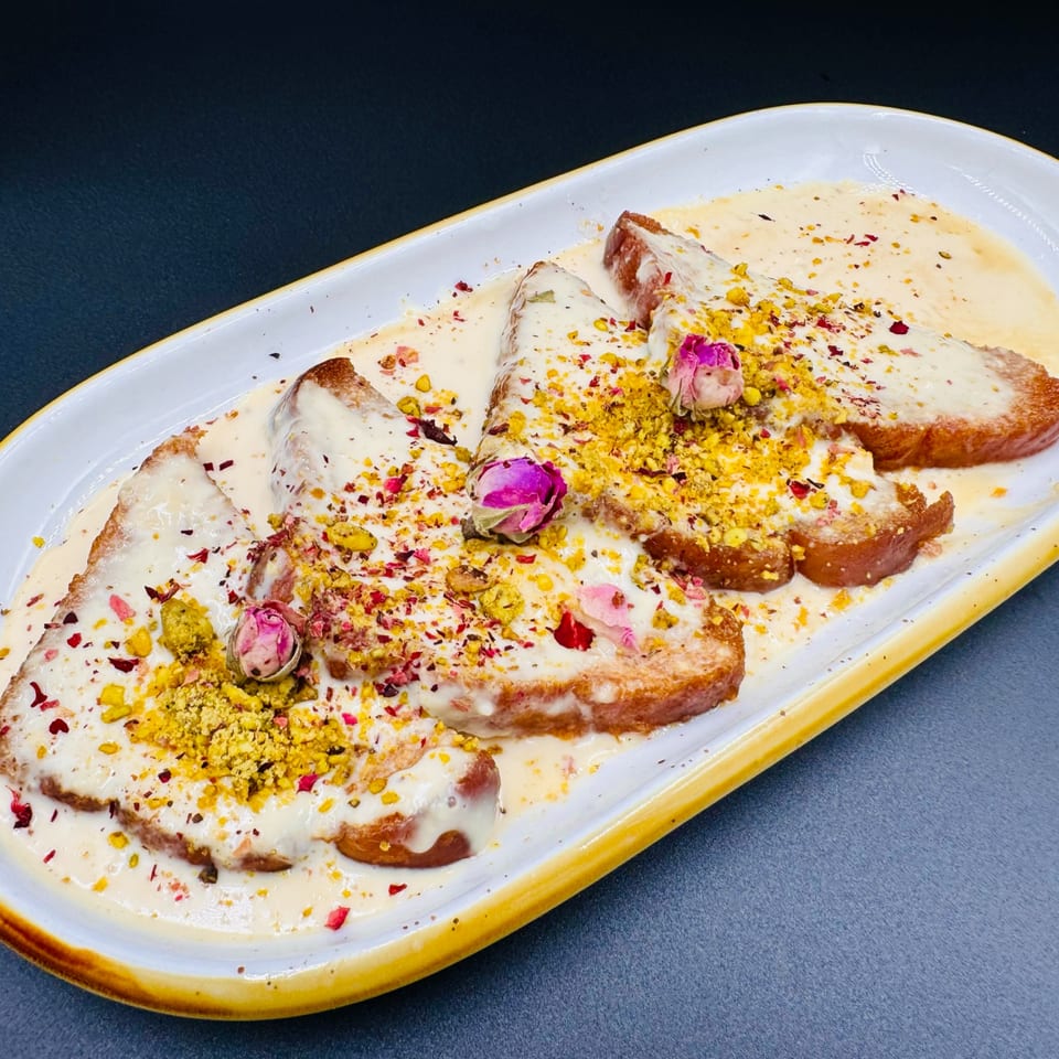 Shahi Tukda, an Indian bread pudding, topped with cream, pistachios, and rose petals.