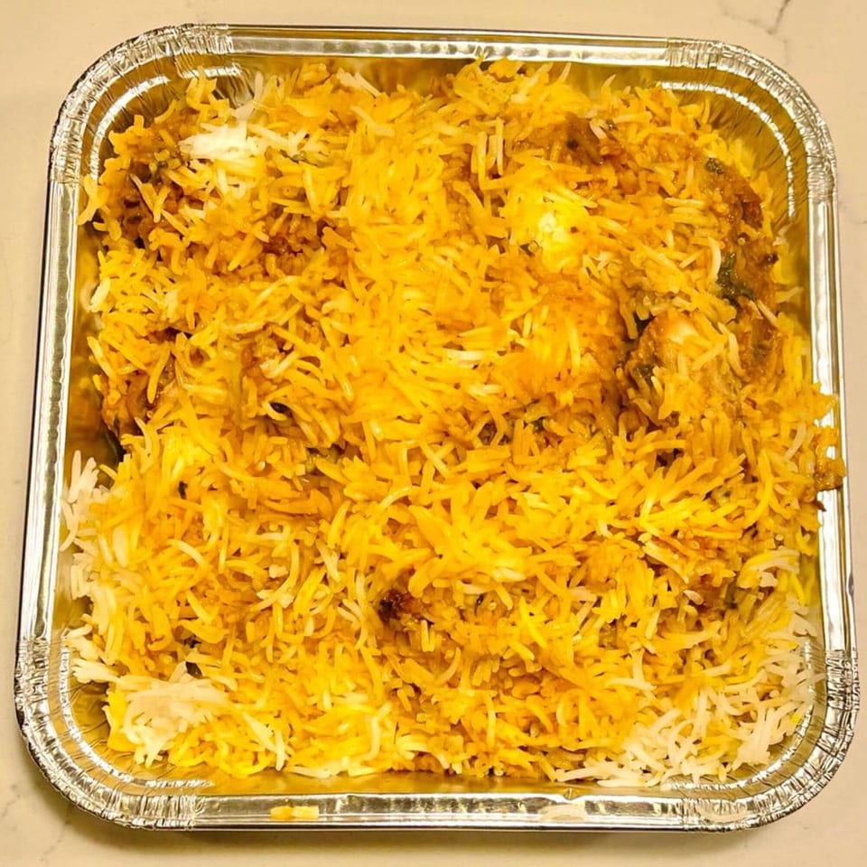 Khan's Kitchen chicken biryani, a flavorful Indian rice dish, in a silver foil takeout container.
