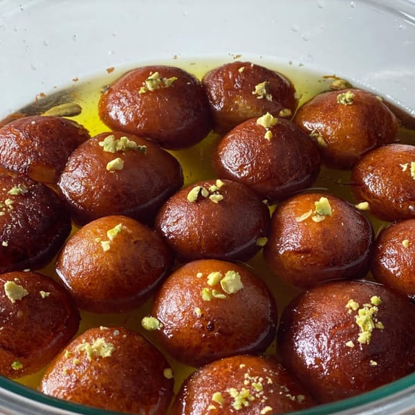 Close-up of Gulab Jamun, Indian fried dough balls soaked in syrup and garnished with pistachios.
