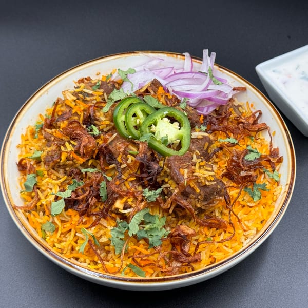 Khan's Kitchen's Indian biryani with meat, rice, fried onions, jalapeños, and red onions.