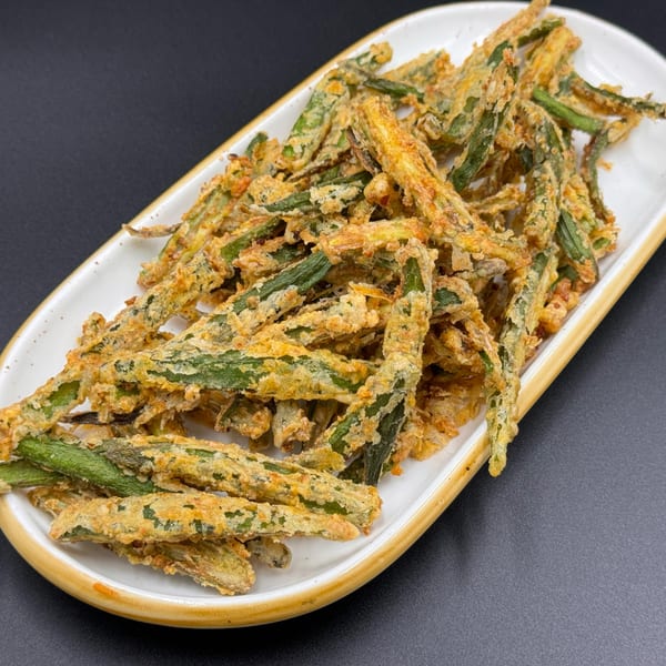Crispy fried okra, a popular Indian snack, served on a white rectangular plate.